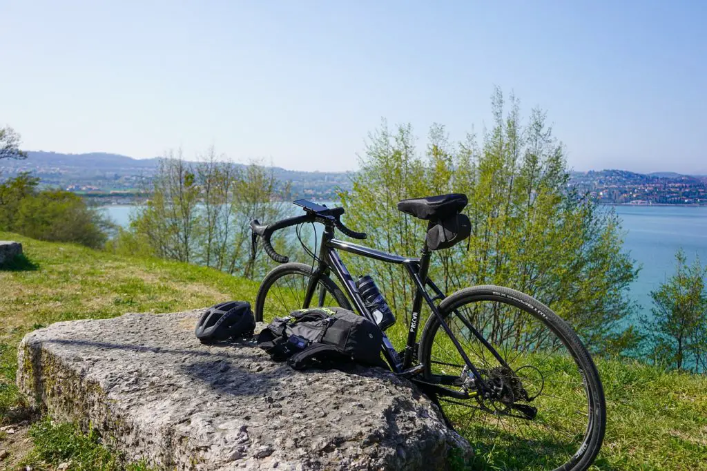 bicycle leaned against a rock beside a lake