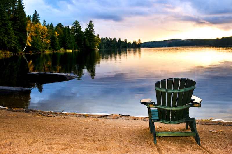 Recliner chair on the lake shore with a sunset in the horison