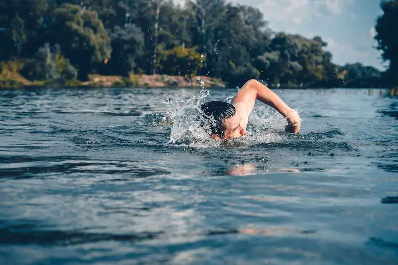 Man swimming in the lake strengthening his body 