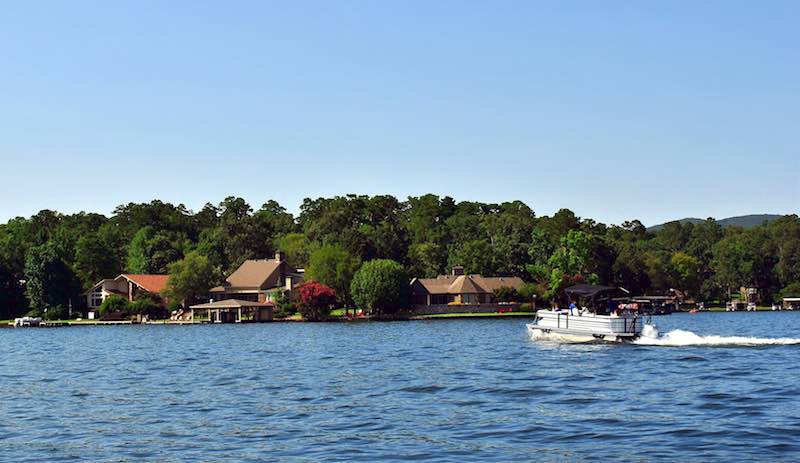Pontoon boat on a lake with lake houses in the background