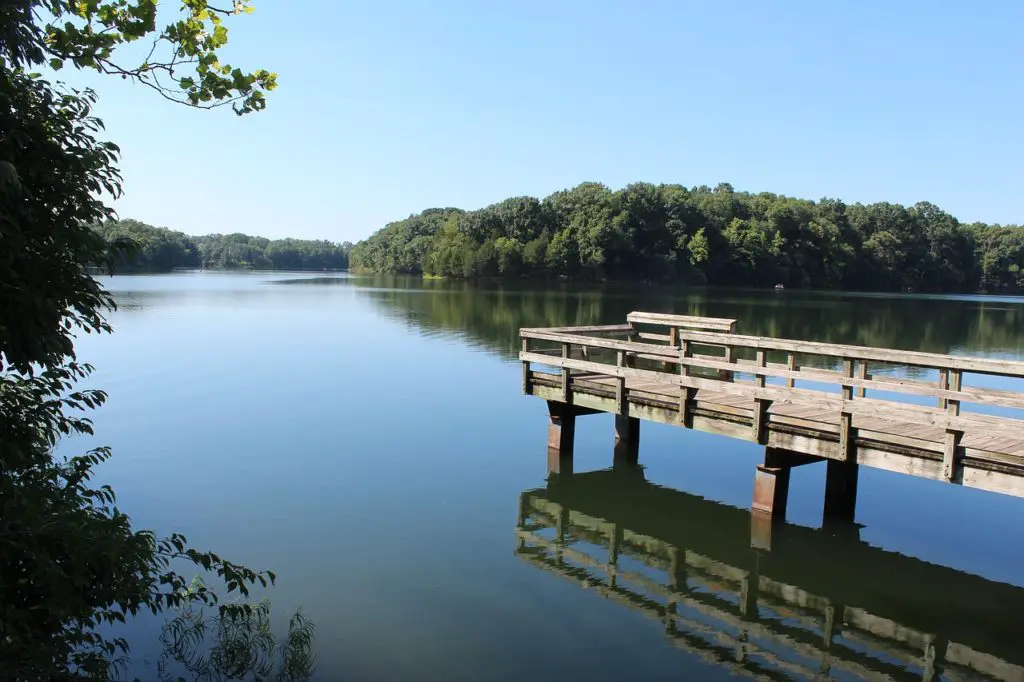 Lake in Shenandoah Valley, Virginia - a wooden dock set in a calm lake surrounded by trees on a sunny day