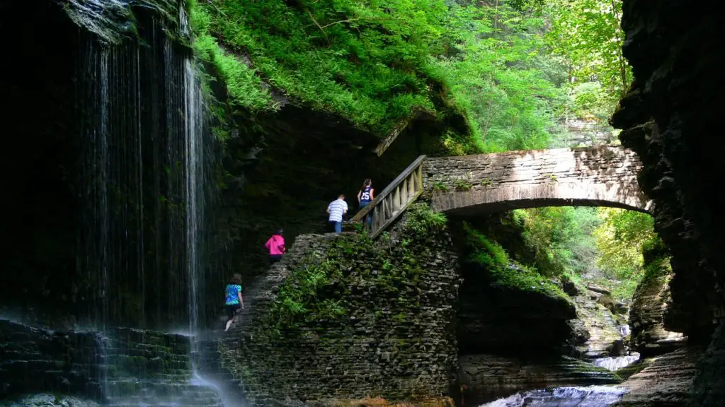 People hiking in Watkins Glen State Park beside a waterfall