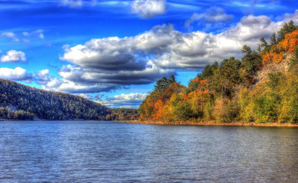 Devils Lake Wisconsin - lake in foreground with hills and trees in background with a blue sky dotted with fluffy white clouds