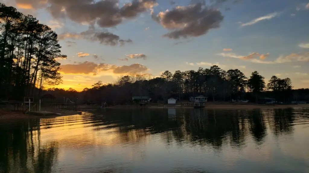 Sunset at Lake Martin. Looking a shoreline with small cottages along the beach.